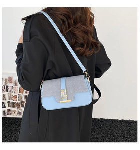 Detail showing light blue leather and striped fabric saddle bag with golden buckle