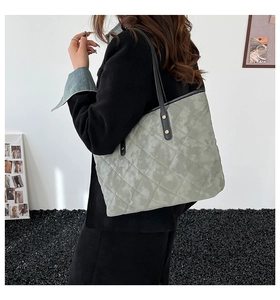 Detail showing the large quilted tote bag with marble texture and black straps on model