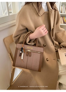 Detail of vintage brown tote with herringbone texture and decorative beaded tassel charm