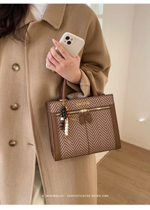 Detail of herringbone fabric tote with leather trim and decorative wooden bead tassel