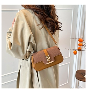 Brown crossbody bag with gold buckle and textured flap shown in a lifestyle setting
