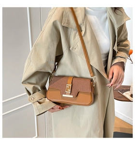 Brown leather crossbody bag with metallic buckle styled on a beige trench coat