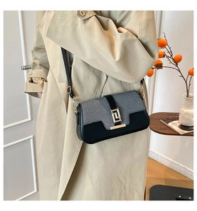 Detail of grey fabric and black leather crossbody bag with golden geometric metal lock