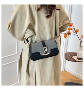 Detail view of contrast leather saddle bag with gold geometric buckle on a model