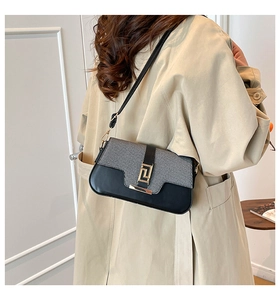 Detail of elegant two-tone shoulder bag featuring grey weave flap and golden metal clasp