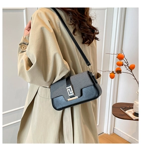 Detail view of structured black leather bag with gold buckle on a fashion model