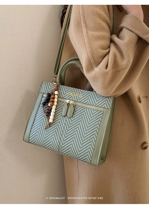 Detail of green chevron woven handbag with wooden beads and leather handle