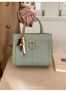 Detail of green woven texture handbag with top handle and wooden bead charm accessory