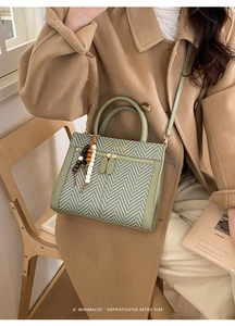 Green chevron knit tote bag with wooden bead charm and crossbody strap on a chair