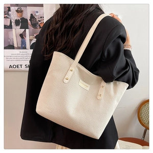 Detail of cream corduroy tote bag showing vertical texture and stylish metal studs