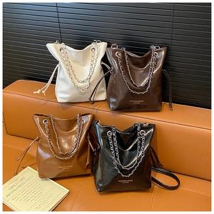 Détail de quatre sacs seaux en cuir brillant avec chaînes en métal et cordon de serrage