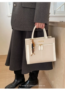 Detail of cream leather and woven crossbody bag with beads charm and gold lettering
