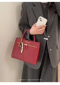 Detail of red rectangular crossbody bag with chevron fabric inlay and beaded charm