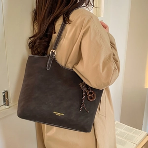 Vintage dark brown matte tote bag with contrast stitching and adjustable strap on model