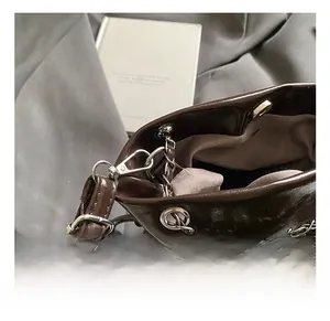 Vue macro d'un sac seau marron foncé brillant avec chaîne en argent et détails de la sangle