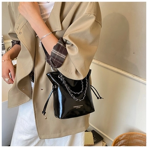 Détail du sac seau en cuir noir brillant avec chaîne argentée et fermeture à cordon