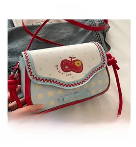 Close-up of sky blue embroidery small square bag with apple pattern and red strap