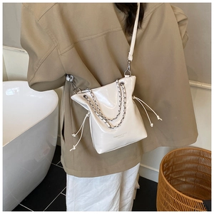 Sac seau blanc chic avec détails plissés et chaîne argentée porté par le mannequin