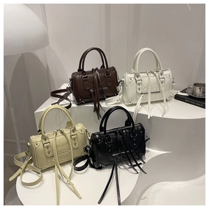 Detailed view of Boston bags with rivets and long tassels in brown, white, yellow, and black