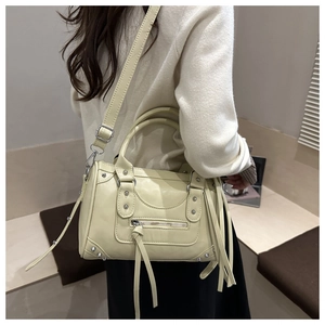 Macro detail of beige Boston bag with silver studs and long fringe tassels