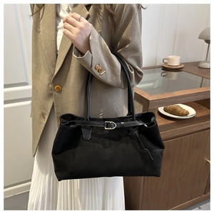 Detail of minimalist black suede tote bag with elegant golden metal buckle and leather strap