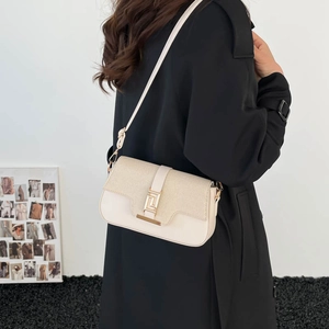 Fashionable beige patchwork crossbody bag with gold buckle worn with a black coat