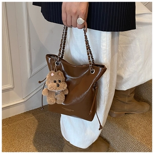 Détail du sac cabas en cuir marron foncé avec chaîne en métal et breloque ours