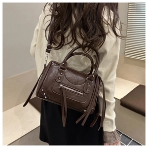 Detail of studded dark brown leather Boston bag showing fringe zippers on a model back