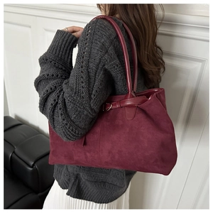 Detailed view of a burgundy suede tote bag shown on model for size and style reference