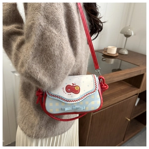 Close-up of a blue and white apple-shaped crossbody bag with a cute red cherry patch
