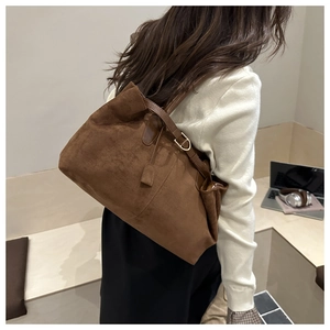 Detail of dark brown suede tote bag with leather straps and metal buckle on side