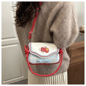 Detail of cute blue polka dot crossbody bag with red apple patch and bow decoration