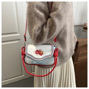 Close-up of blue polka dot handbag featuring red trim and embroidered cherry detail