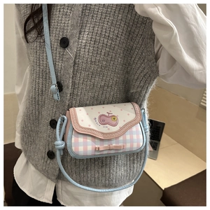 Détail d'un sac à bandoulière à carreaux rose et bleu avec broderie cerise et noeud