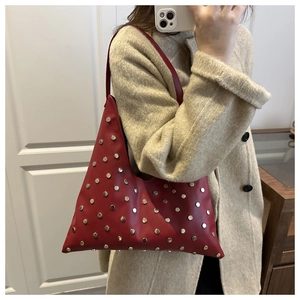 Vue détaillée du sac sous le bras triangulaire rouge foncé avec des rivets argentés décoratifs