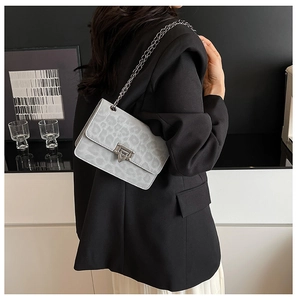 Vista laterale della borsa a catena leopardata grigia con blazer nero per un look trendy
