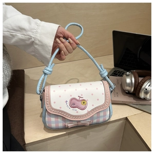 Close-up of pink apple handbag with heart embroidery and bow detail on a wooden desk