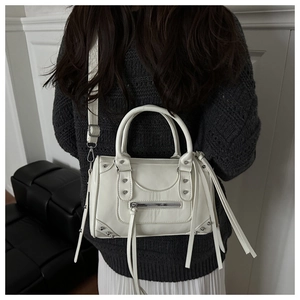 Detail of white vintage Boston bag featuring silver rivets and long leather tassels