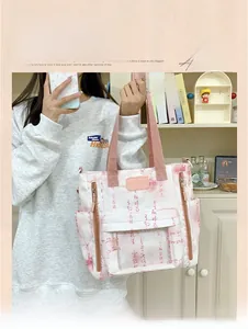 Detail view of the pink canvas tote bag featuring a transparent PVC front pocket and logo