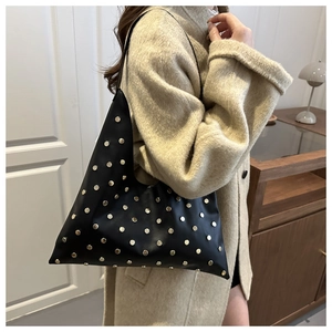 Detail view of black underarm bag with metal rivets and unique geometric triangle shape