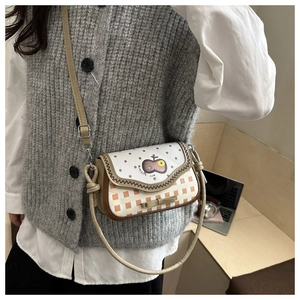Detail of cute crossbody bag featuring polka dot flap and checkered pattern with bow