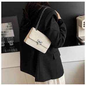 Dettaglio borsa a tracolla beige in pelle con catena d'argento e chiusura girevole
