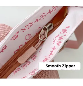 Close-up of a pink bag showing its smooth metal zipper and monogrammed inner lining