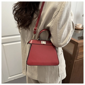 Side view of red leather crossbody bag with metal twist lock and adjustable strap