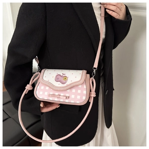 Detailed close-up of a pink bow and apple embroidery on a quilted crossbody bag