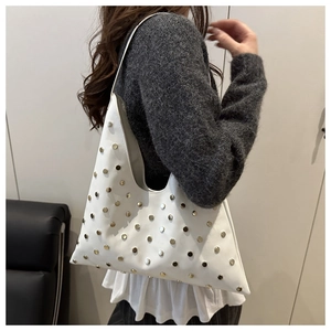 Détail d'un sac bandoulière blanc en cuir avec rivets dorés porté par un mannequin asiatique
