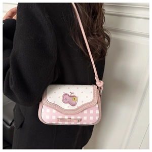 Detail of pink polka dot and plaid crossbody bag with apple embroidery and bow decoration