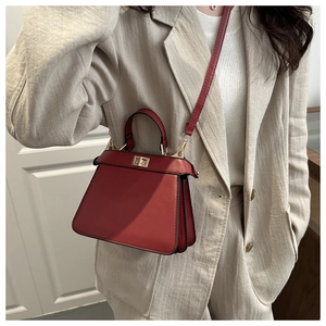 Detail of red matte leather handbag with metal turn-lock and accordion pleat design