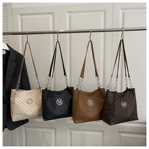 Detail view of four textured tote bags with M print and chain straps in various colors