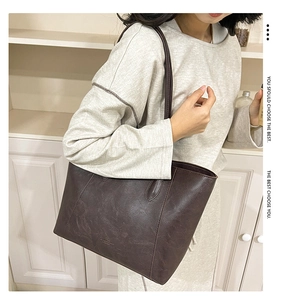 Detail einer dunkelbraunen Leder-Shopper-Tasche mit matter Textur und Markenlogo
